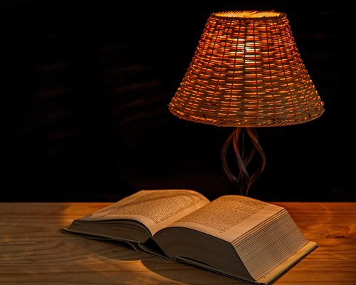 Desk lamp illuminating an open book in a dark room